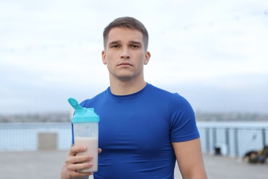 Photo of Athletic man with shaker of protein drink outdoors