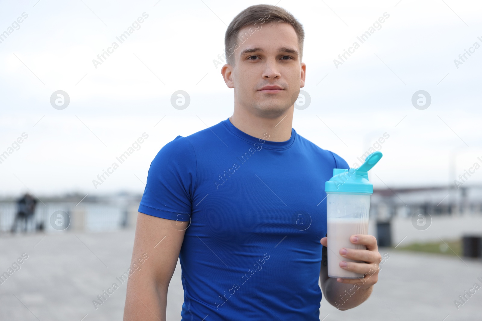 Photo of Athletic man with shaker of protein drink outdoors