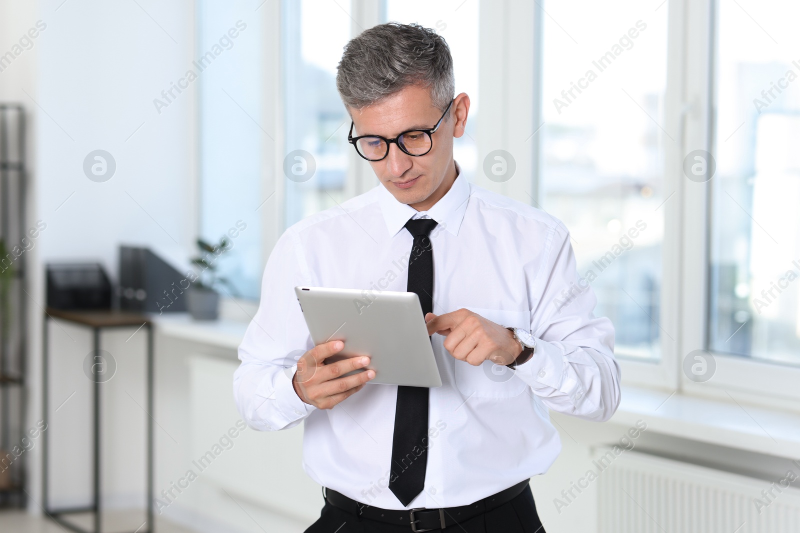 Photo of Businessman with glasses using tablet in office