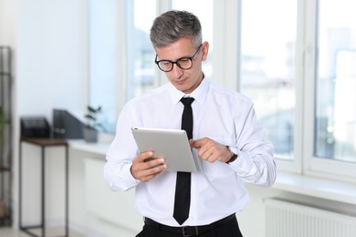 Businessman with glasses using tablet in office