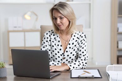 Photo of Businesswoman working on laptop at table in office