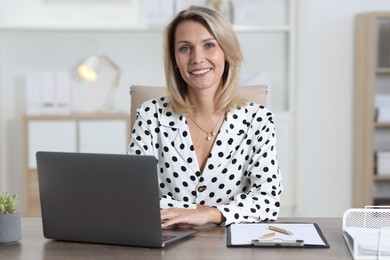 Photo of Businesswoman working on laptop at table in office