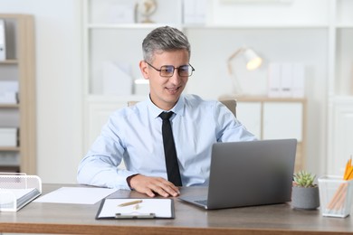 Photo of Businessman working with laptop at table in office