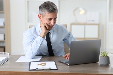 Photo of Businessman working with laptop at table in office