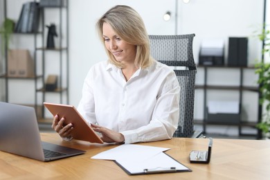 Photo of Businesswoman using tablet at table in office