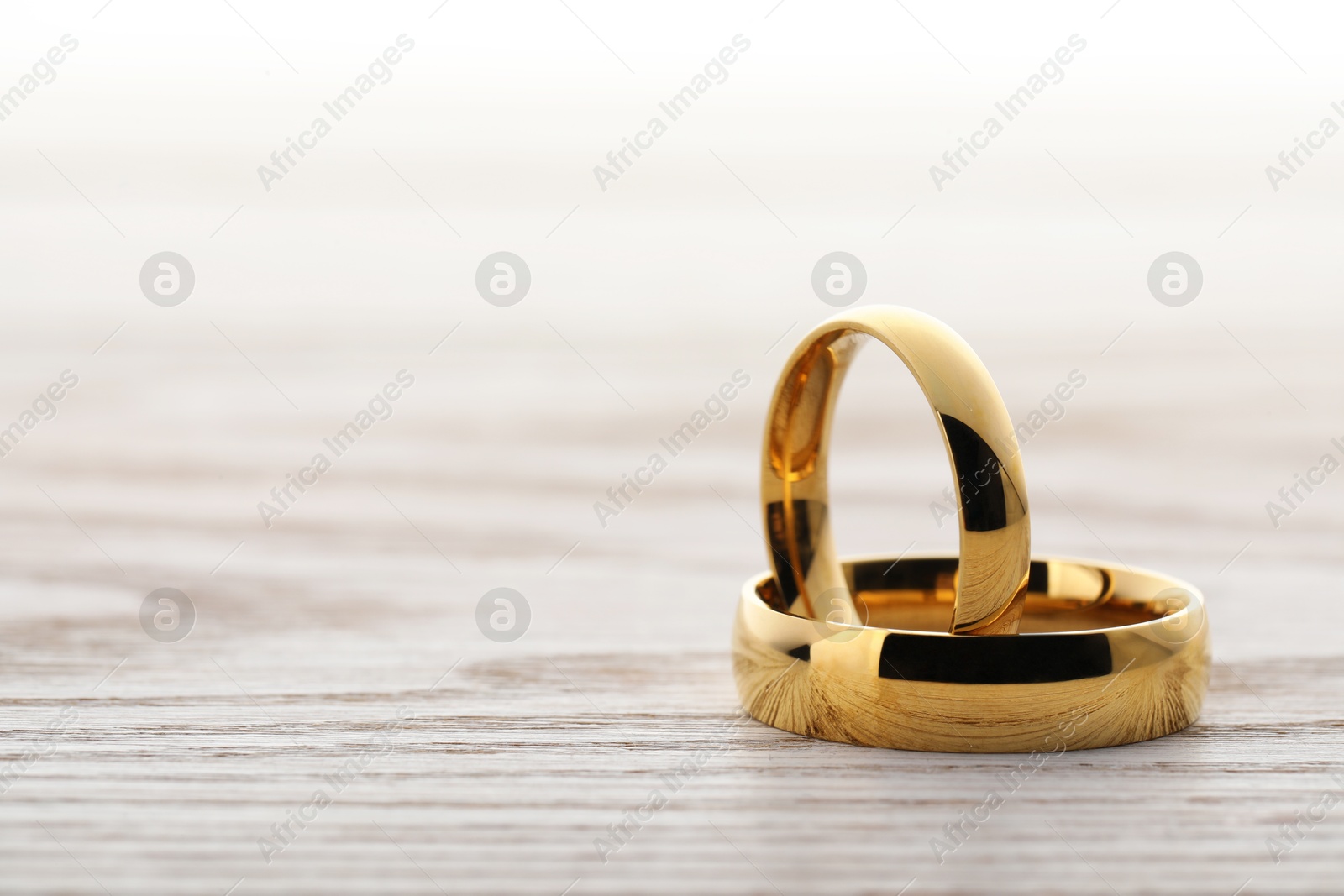 Photo of Beautiful golden wedding rings on wooden table, space for text