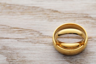 Beautiful golden wedding ring on wooden table, closeup. Space for text