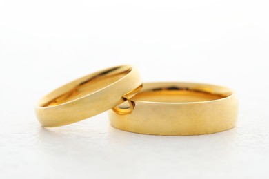 Photo of Beautiful golden wedding ring on white table, closeup