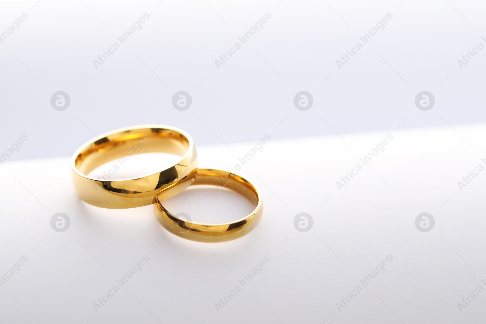 Photo of Beautiful golden wedding rings on white background, space for text