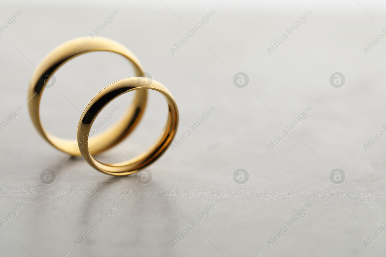 Photo of Beautiful golden wedding rings on gray background, closeup. Space for text