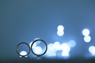 Beautiful golden wedding rings against blurred lights, space for text