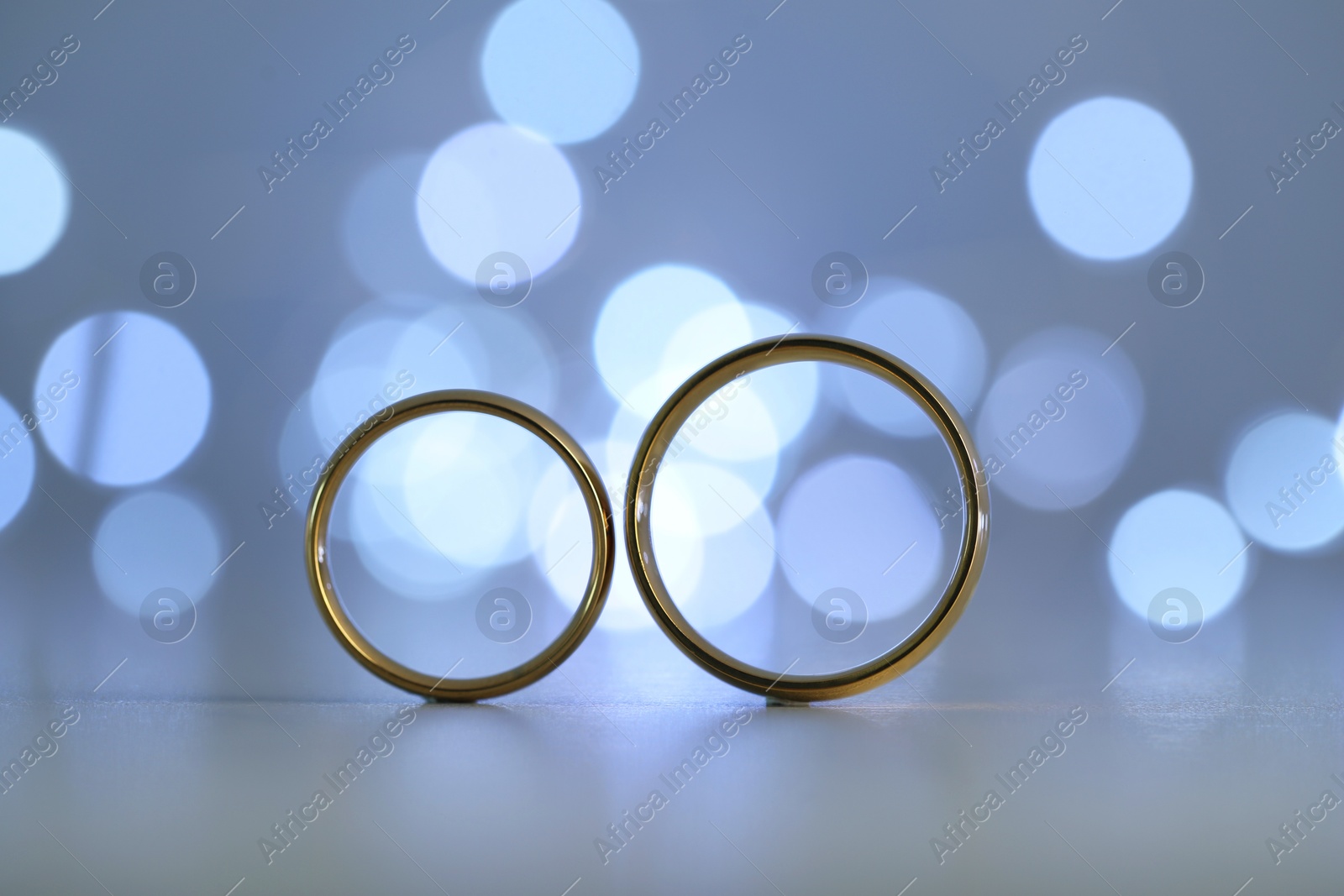 Photo of Beautiful golden wedding rings against blurred lights