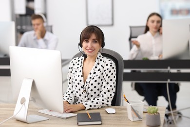 Photo of Saleswoman talking to client via headset at desk in office