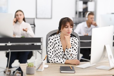 Saleswoman talking to client via headset at desk in office