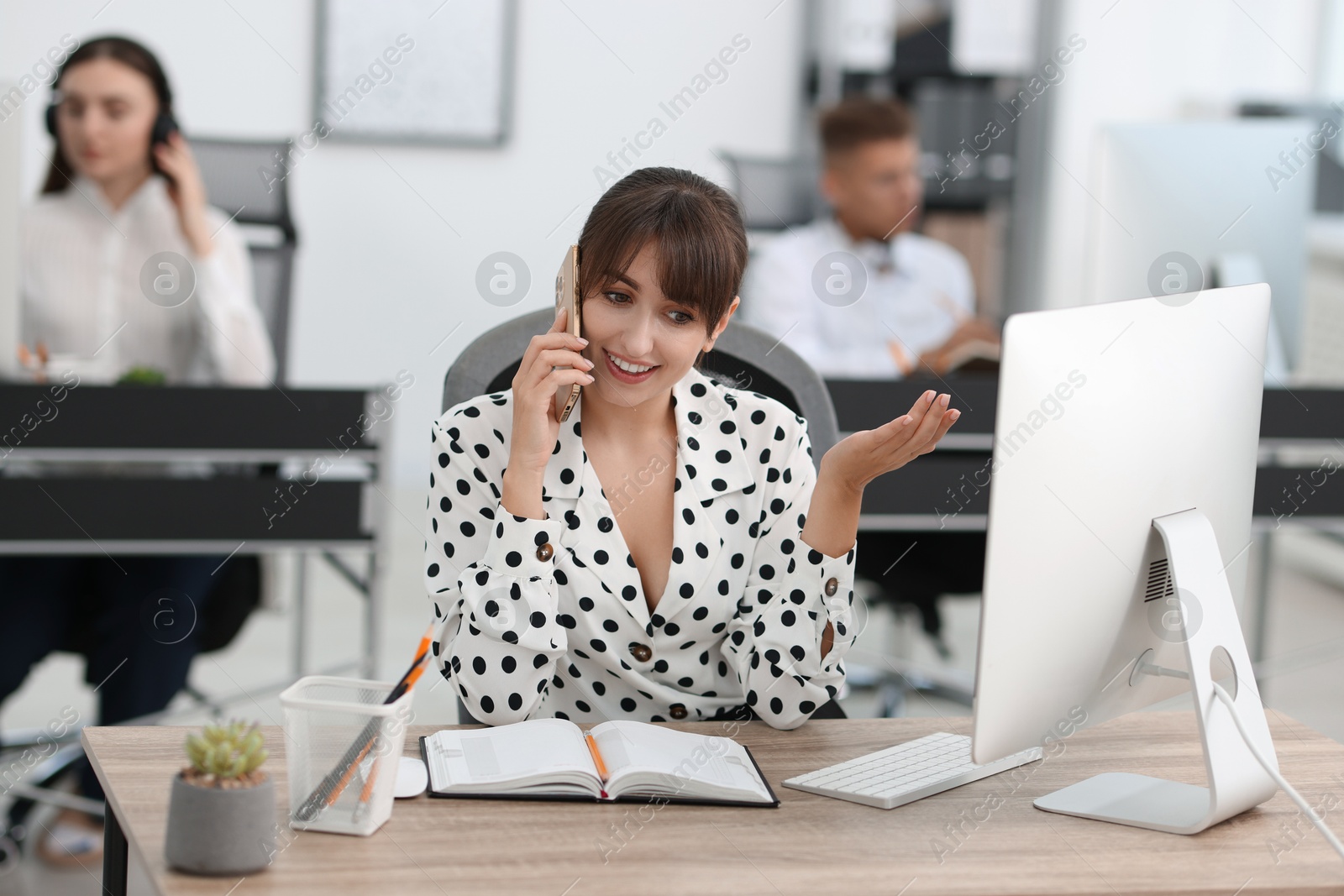 Photo of Saleswoman talking on phone at desk in office