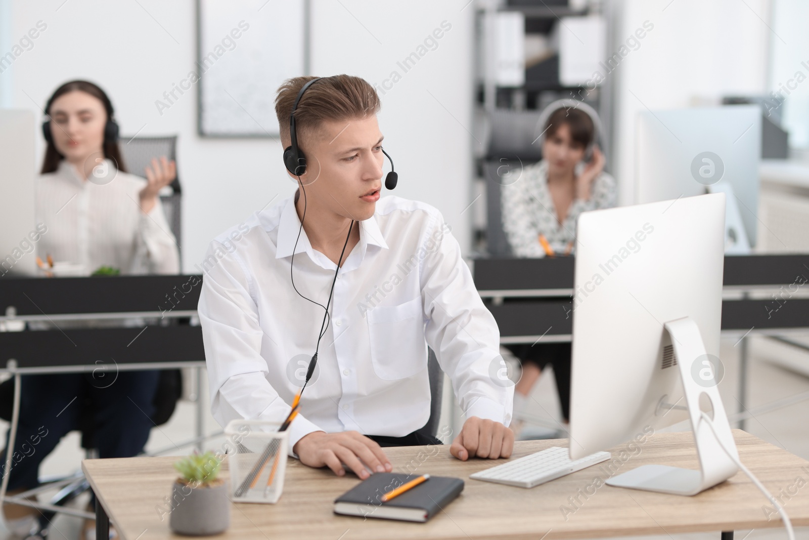 Photo of Salesman talking to client via headset at desk in office