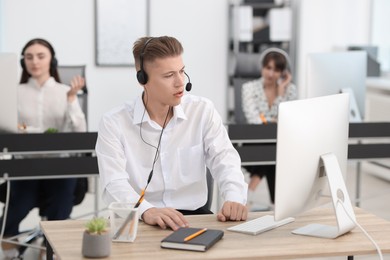 Photo of Salesman talking to client via headset at desk in office