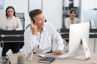 Photo of Salesman talking to client via headset at desk in office