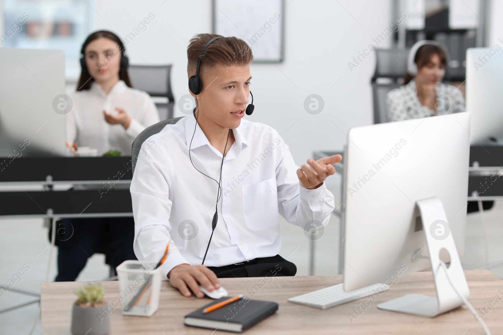 Photo of Salesman talking to client via headset at desk in office