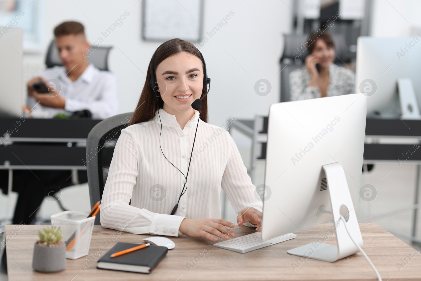 Photo of Saleswoman talking to client via headset at desk in office