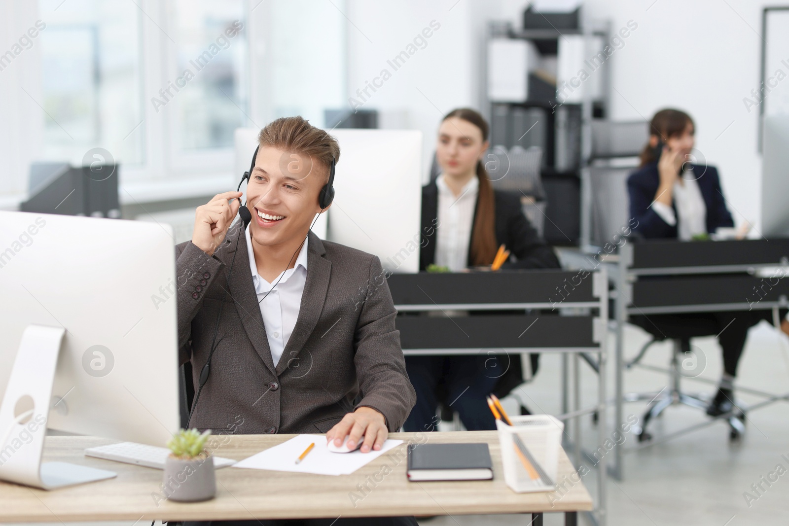 Photo of Salesman talking to client via headset at desk in office