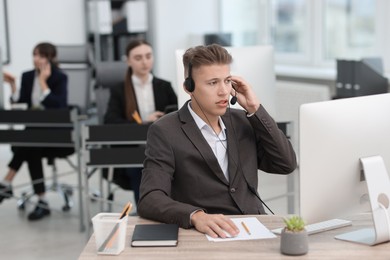 Photo of Salesman talking to client via headset at desk in office