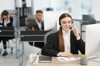 Photo of Saleswoman talking to client via headset at desk in office