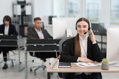 Photo of Saleswoman talking to client via headset at desk in office