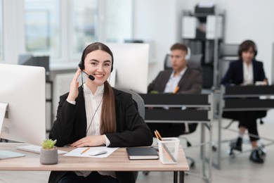 Photo of Saleswoman talking to client via headset at desk in office