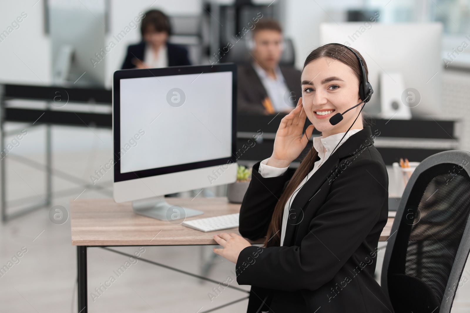 Photo of Saleswoman talking to client via headset at desk in office