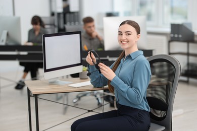 Photo of Saleswoman with headset at desk in office