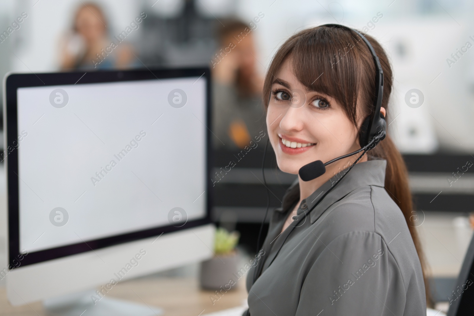 Photo of Saleswoman talking to client via headset at desk in office