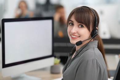 Photo of Saleswoman talking to client via headset at desk in office