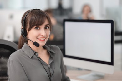 Photo of Saleswoman talking to client via headset at desk in office