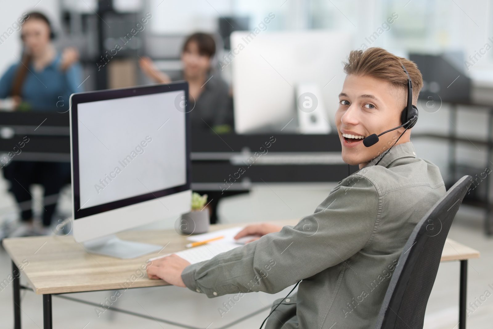 Photo of Salesman talking to client via headset at desk in office