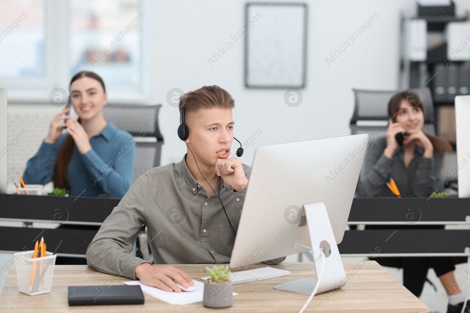 Photo of Salesman talking to client via headset at desk in office