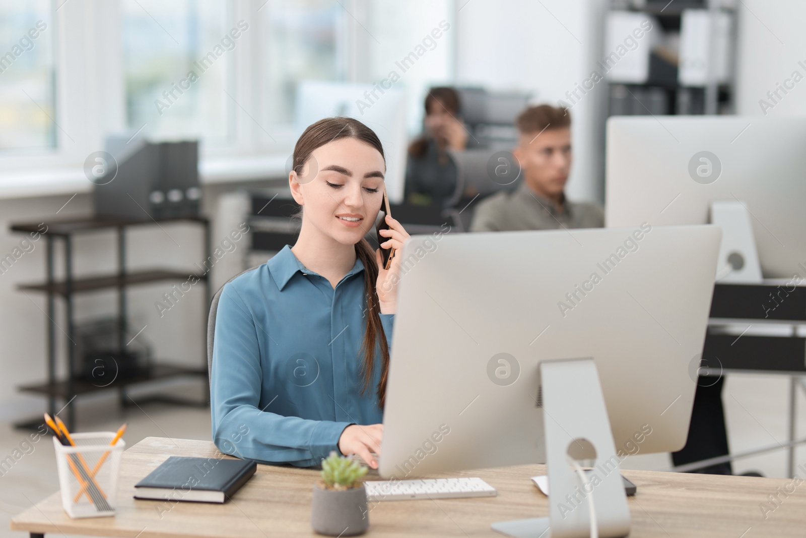 Photo of Saleswoman talking on phone at desk in office