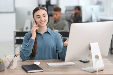 Photo of Saleswoman talking on phone at desk in office