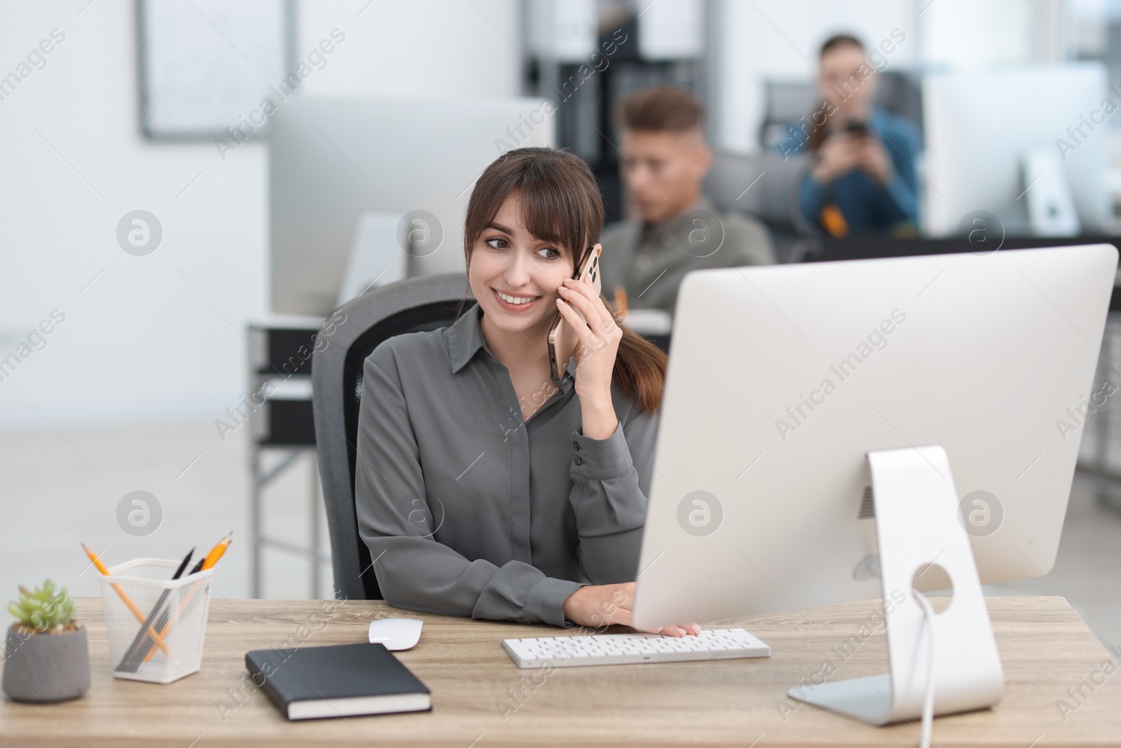 Photo of Saleswoman talking on phone at desk in office