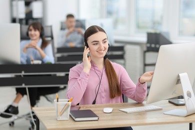 Photo of Saleswoman talking to client via headset at desk in office