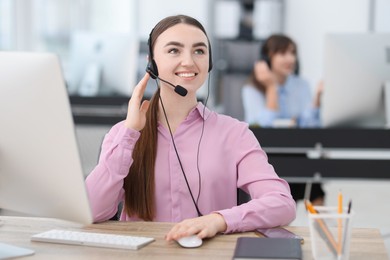 Photo of Saleswoman talking to client via headset at desk in office