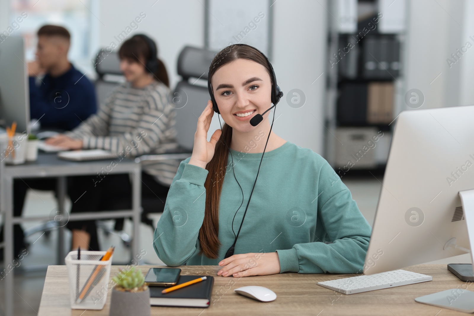 Photo of Saleswoman talking to client via headset at desk in office