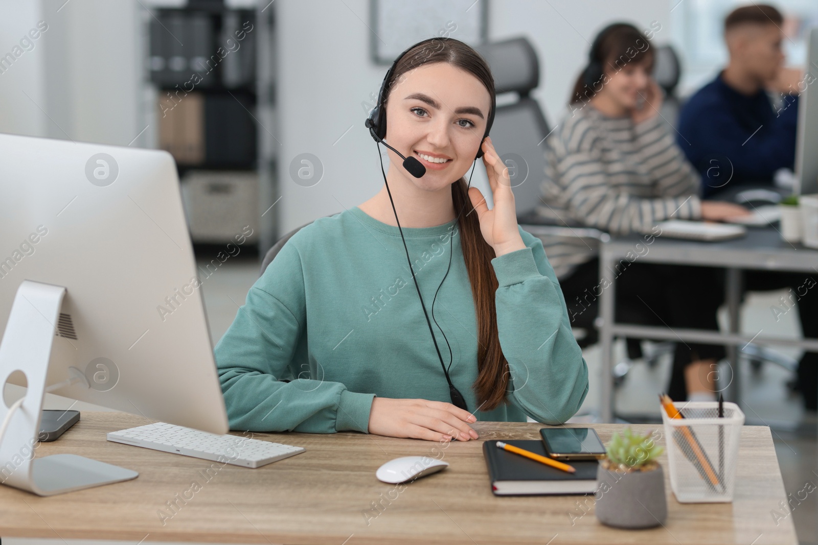 Photo of Saleswoman talking to client via headset at desk in office