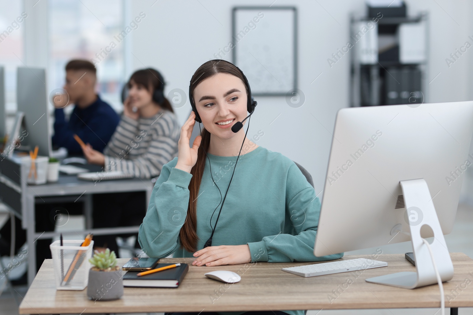 Photo of Saleswoman talking to client via headset at desk in office