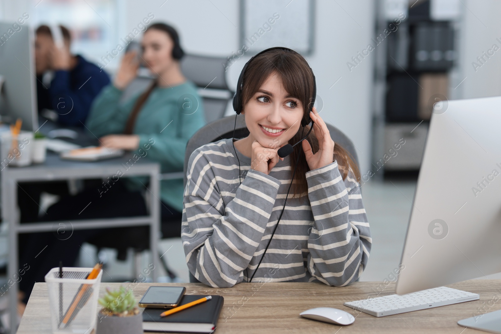 Photo of Saleswoman talking to client via headset at desk in office