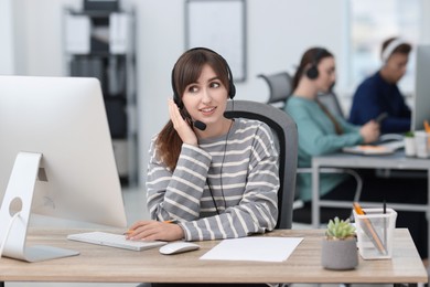 Photo of Saleswoman talking to client via headset at desk in office