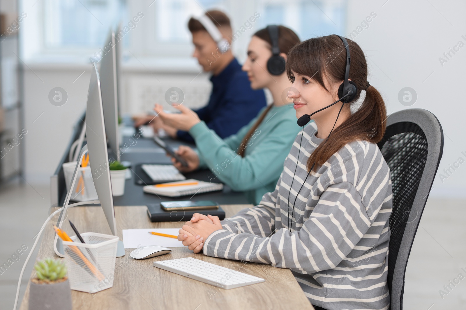 Photo of Saleswoman talking to client via headset at desk in office