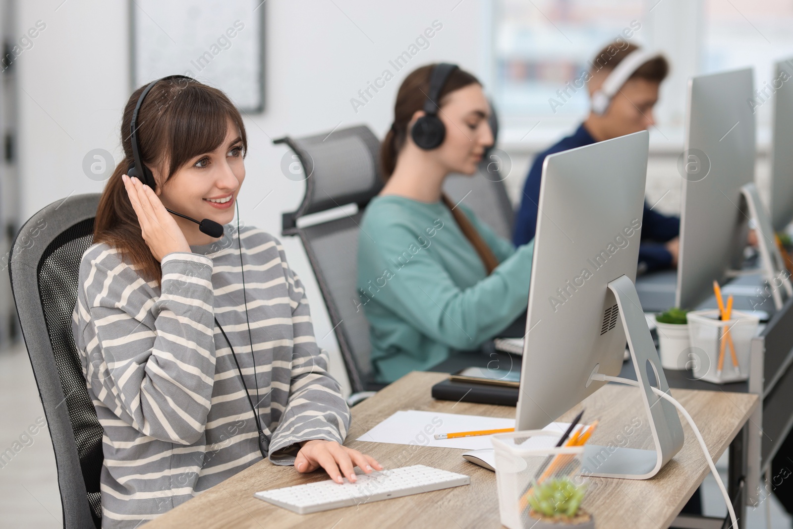 Photo of Saleswoman talking to client via headset at desk in office