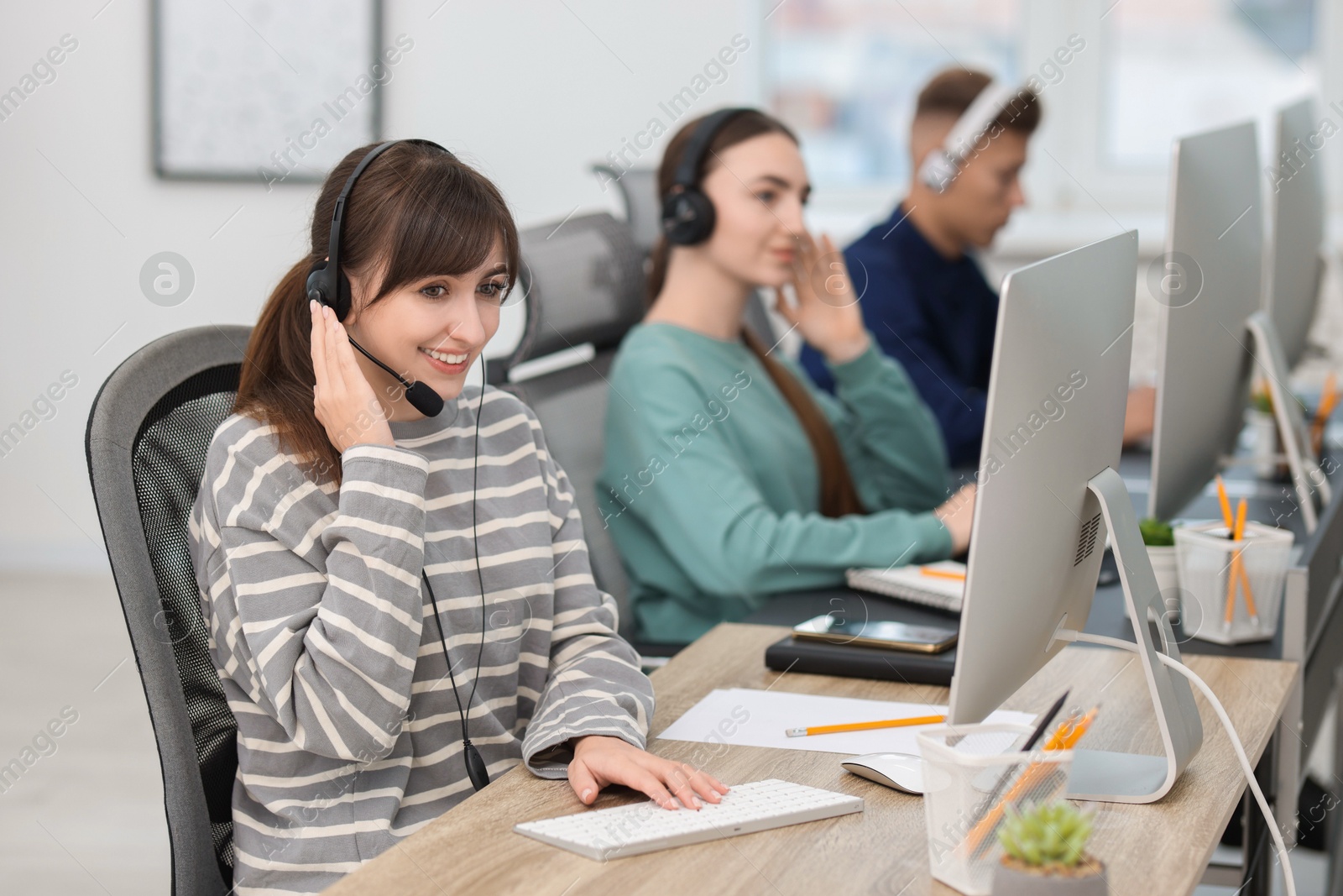 Photo of Saleswoman talking to client via headset at desk in office