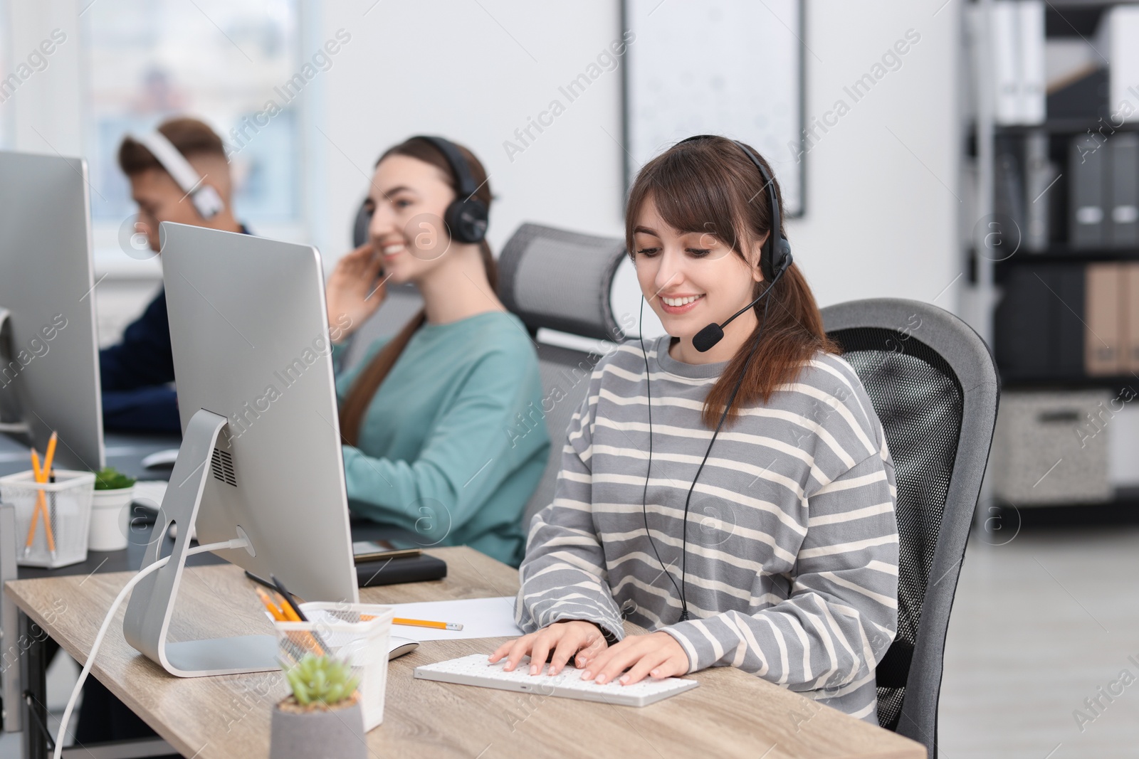 Photo of Saleswoman talking to client via headset at desk in office